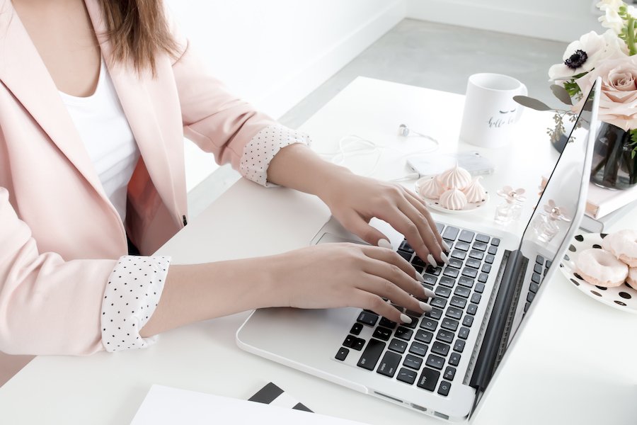 woman in pink blazer with laptop